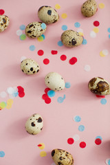 Quail eggs on a pink background with colorful confetti