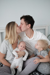 Fototapeta na wymiar Family portrait: young mom and dad with his 2 years old son and 2 month old baby