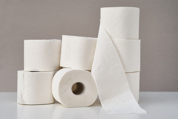 Stacked toilet paper rolls on a gray background. Hygiene concept