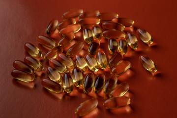 fish oil capsules on red background close-up