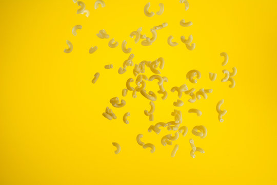 Zero Gravity Food Concept. Flying Uncooked Pasta On Yellow Background With Copy Space.