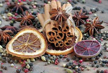 traditional spices for mulled wine. cinnamon sticks, anise stars, cardamom, pepper, and dry citruses on a wooden table.