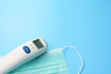 medical concept. corona virus covid-19. thermometer and face mask on blue desk. free copy space for your text