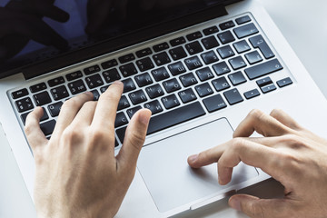 Man hands typing on laptop keyboard in sunny office, business and technology concept. Close up