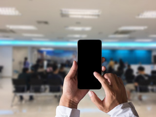 Hand holding white mobile phone with blank white screen  in bank.