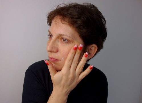 40 Years Old Woman Applying Cream On Her Face