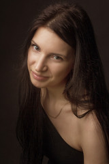 portrait of a brunette on a dark gray studio background in a black dress