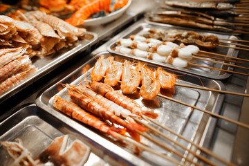 Seafood on wooden sticks for grilling.