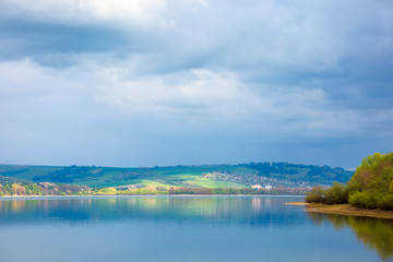 Fototapeta na wymiar lake in mountains. cloudy day in springtime. beautiful scenery of high tatra mountains in dappled light. gorgeous landscape of liptovska mara, slovakia