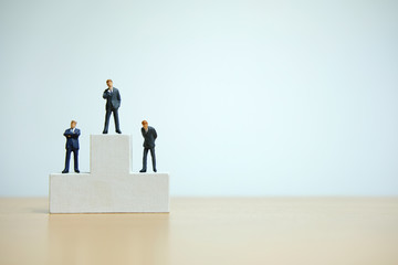 Business conceptual photo – miniature of businessman stands on wooden podium