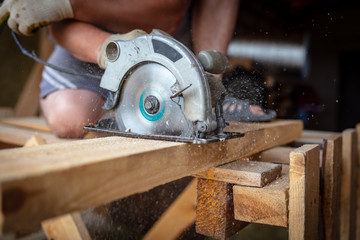 A worker saws a wooden beam.