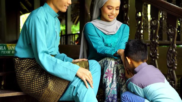 boy greeting to malay couple sitting on stair way