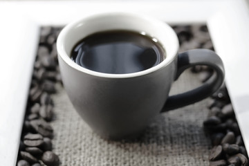 cup of coffee and coffee grains on burlap.