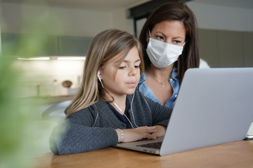 Woman at home with kid helping with online teaching - coronavirus