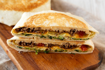 Tasty Homemade Beef Crunchwrap Quesadilla on a rustic wooden board, low angle view. Close-up.