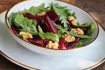 Vegetarian food. Healthy Beet Salad with fresh sweet baby spinach, arugula, nuts
