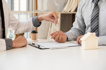 Real estate agent broker hand over the house key to the new owner after completing the signing according to agreement renting a house and buy house insurance Home insurance concept