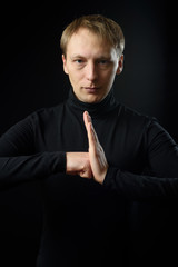 Portrait of determined goodlooking man wearing black shirt, black background.