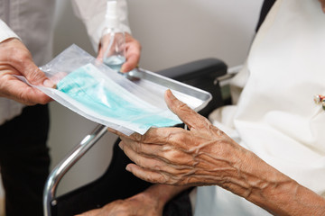 Elderly woman get a mask from caregiver to protect from coronavirus covid-19