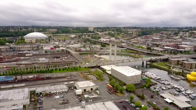 Aerial, tracking, drone shot overlooking traffic on a bridge and a  large duck-float at the Thea Foss Waterway, cloudy day, in Washington state, USA