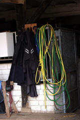 Bunte Seile und Jacken in einem Pferdestall auf einem Gestüt und Bauernhof bei Sonnenschein in...