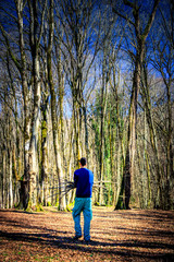 alone adventurer collecting woods for fire. solo man walking in the forest and collecting woods and...