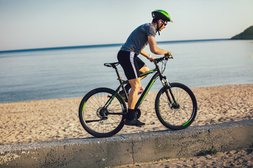 Fototapeta na wymiar Man ride mountain bike on the beach. Sport and active life concept.