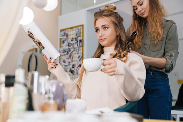 Displeased young beautiful woman client with hair stylist