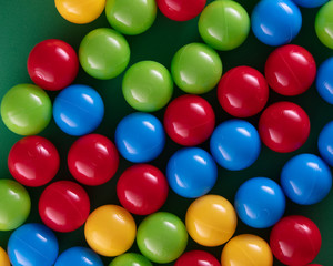 Multi-colored plastic balls on a green background top view, high resolution. 