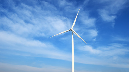 Wind turbine against cloudy blue sky background