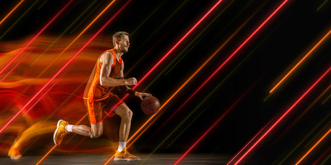 Creative sport and neon lines on dark background, flyer, proposal. Male basketball player training...