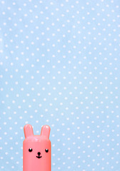 Simple cute bright Bunny on a soft pastel blue polka dots background. Template for a cute bright card for Easter, birthday.