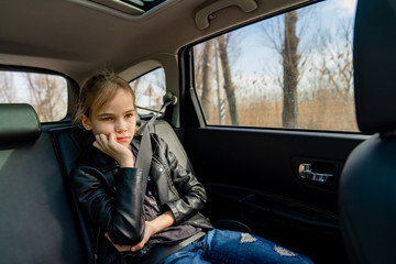 sad teen girl in seat back of car look ahead