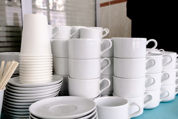 Exposed on stacks of white clean ceramic cups and saucers. The dishes in the restaurant are prepared for tea drinking and coffee drinking.