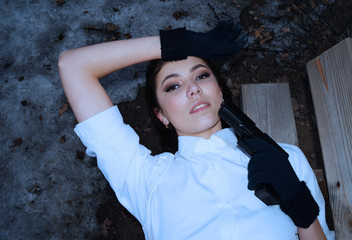 Young woman lies on a bench in a white shirt with a gun
