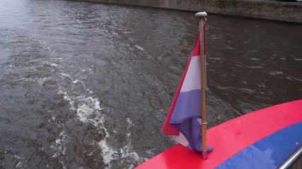 Medium shot of the Netherlands flag while boat Riding Across The Amsterdam Canal In Netherlands - Powered by Adobe