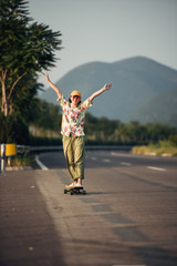 Fototapeta na wymiar A young Asian girl skateboards at sunset