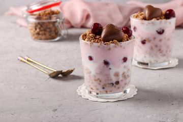 Chocolate granola with yogurt, cherries and nuts, decorated with chocolate hearts in glasses on a gray background, Close up