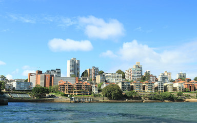 Modern city buildings by the river under the blue sky on sunny day