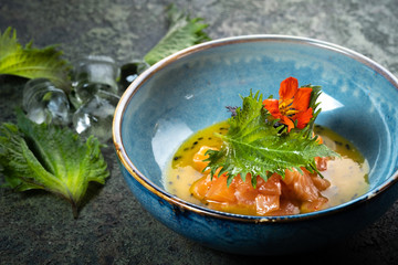 Salmon fillet ceviche with shiso leaves in a blue bowl. Fresh fish tartare