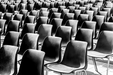 Rows of empty black chairs, prepared for event.