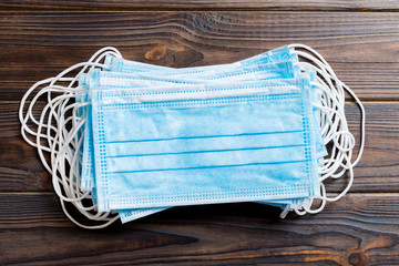 Pile of protective medical masks on wooden background. Respiratory syndrome. Protect your health...