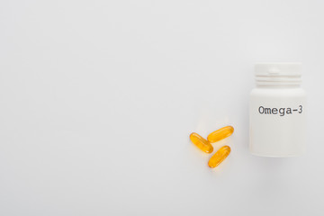 Top view of container with omega-3 lettering and capsules on white