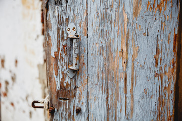 Old wooden door with remnants of old paint. A handle is bolted to the door.