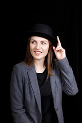 cute young girl in hat and gray jacket on black background