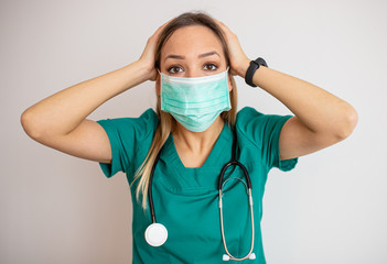 Young nurse feeling extremely shocked and surprised, anxious and panicking, with a stressed and horrified look against white wall – stock image