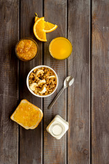 Granola for healthy breakfast. Still life composition with fruits and toast on wooden background top-down