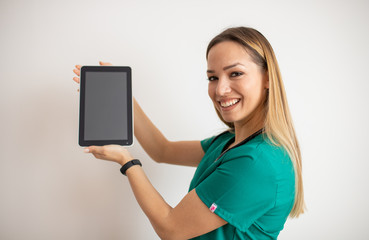 Smiling young nurse pointing at tablet with blank screen isolated on white - Powered by Adobe