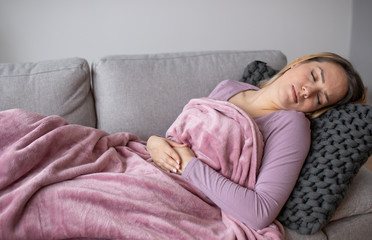 Woman having stomach issues / problems while lying on the couch