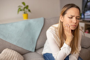Attractive young woman suffering from toothache. Woman holding her cheek in pain